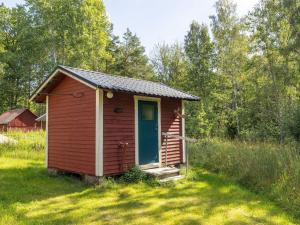 einen kleinen roten Schuppen mit blauer Tür auf einem Feld in der Unterkunft Chalet Mjöshult - SND157 by Interhome in Hjorted