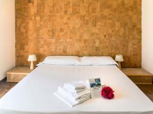 a white bed with towels and a red flower on it at Apartment Comfort by Interhome in Riva del Garda
