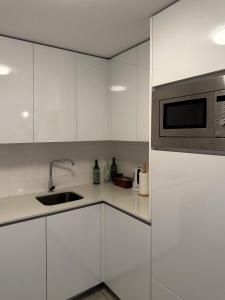 a white kitchen with a sink and a microwave at Casa Sousa - 3rd generation (Apart.2) in Boticas