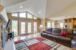 a living room with a leather couch and a tv at White Swan Lake Home with Decks and Private Beach! in Bigfork