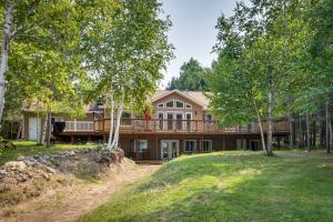 a large house with a deck and trees at White Swan Lake Home with Decks and Private Beach! in Bigfork