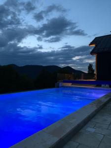 a blue swimming pool at night with mountains in the background at Cabanele CARMEL in Muntele Rece
