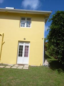 a yellow house with a white door at Kanell in Gros-Morne