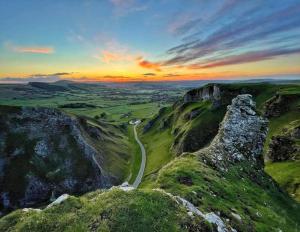 a road on the side of a mountain at sunset at Peak District Self Catering Holiday Home in Glossop