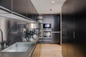 a kitchen with black cabinets and a stainless steel counter top at The Instagood Apartment - Covent Garden - by Frankie Says in London