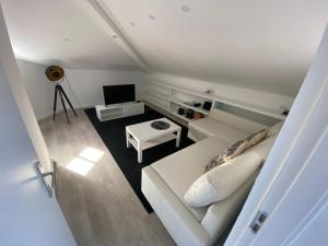 uma sala de estar com um sofá branco e uma televisão em Casa da Capela em Aveiro
