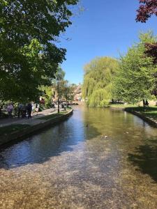 Une rivière avec des gens qui marchent sur son côté dans l'établissement Historic Cotswold Chic Style for UK staycation, à Bourton-on-the-Water
