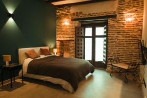 um quarto com uma cama e uma parede de tijolos em Casa de los Mendoza - Casa Solariega en el casco histórico em Alcalá de Henares