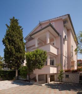 um grande edifício rosa com árvores em frente em Apartment Juliette em Zadar