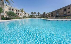 una gran piscina azul con palmeras y edificios en Primera línea, magníficas vistas al mar y a la playa, en Retamar