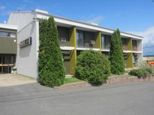 un bâtiment avec une rangée d'arbres devant lui dans l'établissement Motel Le Martinet, à La Pocatière