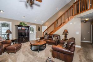 a living room with leather furniture and a staircase at Black Bear Lodge in Oakland