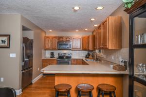 a kitchen with wooden cabinets and a kitchen island with stools at Black Bear Lodge in Oakland +65 photos