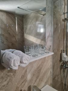 a bathroom with a shower with towels and glasses on a shelf at Secret Garden Sweet Home in Brad