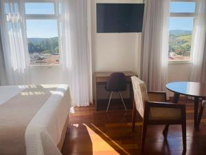 安帕羅的住宿－Grande Hotel Amparo，一间卧室配有一张床、一张桌子和一张桌子