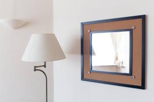 a floor lamp and a mirror on a wall at Seashell - annex in Selsey