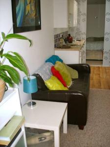 a living room with a black couch with colorful pillows at Seashell - annex in Selsey