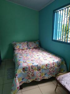 um quarto com uma cama com uma colcha e uma janela em Pousada Joao & Maria em Pirenópolis