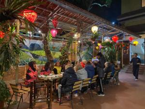 Tam Coc Family Hotel في نينه بينه: مجموعة من الناس يجلسون على طاولة في مطعم