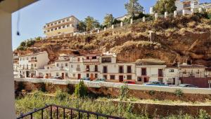 un grupo de edificios en una colina con coches aparcados en Casas Rurales El Tajo, en Setenil