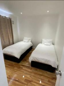 two beds in a small room with wood floors at Twin/King private bedrooms in beautiful homestay with private parking in Forest Hill