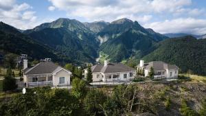 a house on a hill with mountains in the background at Qafqaz Tufandag Mountain Resort Hotel in Gabala