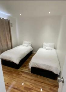 una camera con 2 letti, lenzuola bianche e pavimenti in legno di Twin/King private bedrooms in beautiful homestay with private parking a Forest Hill