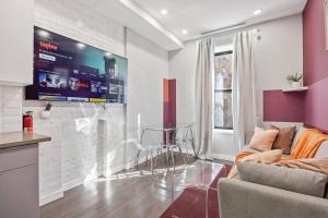 - un salon avec un canapé et une télévision murale dans l'établissement SWJ 2nd - Times SQ, Brooklyn Bridge, LGA in 15 min, à New York