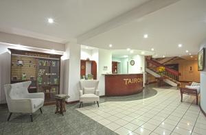 a lobby with two chairs and a table and a pharmacy at Apartotel Tairona in San Pedro