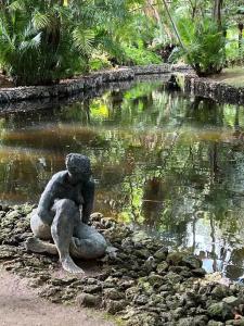 uma estátua de uma mulher sentada em frente a um lago em Azor International House em Ponta Delgada