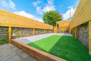 a backyard with a stone wall and a green lawn at Kim's City Escape in Cardiff