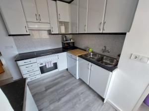 uma pequena cozinha com armários brancos e um lavatório em Alia em Madri