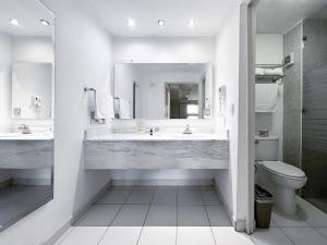 een witte badkamer met 2 wastafels en een toilet bij Quinta Dorada Hotel & Suites in Saltillo