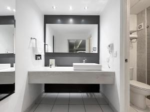 La salle de bains blanche est pourvue d'un lavabo et d'un miroir. dans l'établissement Quinta Dorada Hotel & Suites, à Saltillo