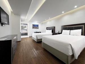 a hotel room with two beds and a flat screen tv at Quinta Dorada Hotel & Suites in Saltillo