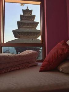 Zimmer mit einem Fenster und Kissen auf einem Bett in der Unterkunft Annapurna Guest House and Rooftop Restaurant in Bhaktapur