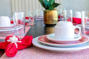 einem Tisch mit roten und weißen Platten und einer Tasse darauf. in der Unterkunft Crôa Residence in Maragogi