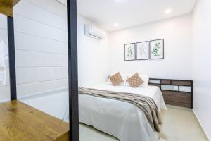 Schlafzimmer mit einem Bett mit weißen Wänden in der Unterkunft Crôa Residence in Maragogi