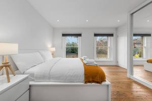 ein weißes Schlafzimmer mit einem Bett und zwei Fenstern in der Unterkunft Flourish Apartments - The Annex - Dulwich Village in London