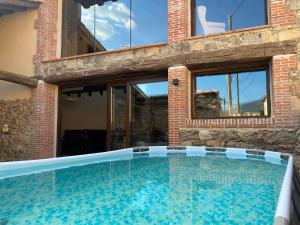 una piscina frente a una casa con ventanas en La Casa del Guarda - Turismo Sotosalbos, en Sotosalbos