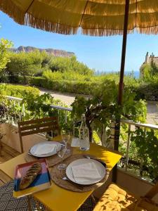 a table with plates and wine glasses and an umbrella at Le repaire de la Vierge bohème vue mer in Cassis