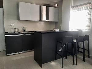 a kitchen with a black counter and stools at Newly Renovated 1Bd Apt in Heart of Osu in Accra