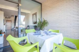 comedor con mesa blanca y sillas verdes en Confortable Beach Appartment with Views to the Sea, en Puzol