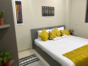 een bed met gele en witte kussens in een kamer bij Newly Renovated 1Bd Apt in Heart of Osu in Accra