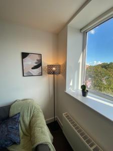 a room with a window and a chair and a lamp at Lovely 1 BR flat in Sutton NH116 in Sutton