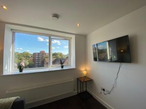 a room with a flat screen tv and a window at Lovely 1 BR flat in Sutton NH116 in Sutton