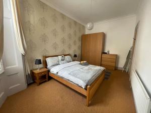 een slaapkamer met een groot bed en een houten hoofdeinde bij Stunning West End Flat! in Glasgow