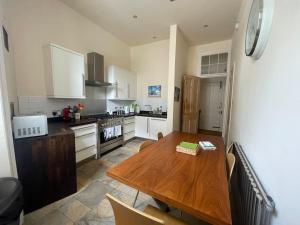 eine Küche mit einem Holztisch und eine Küche mit weißen Schränken in der Unterkunft Stunning West End Flat! in Glasgow