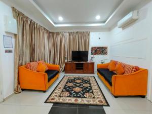 a living room with two orange couches and a television at RoofTop Villa in Malacca