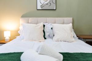 Cama blanca con almohadas blancas y manta verde en Innovation House, en Burnley